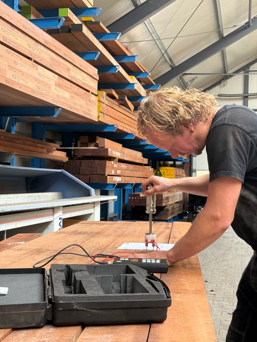 Jeroen meet het vochtpercentage van een balk hout met de houtvochtmeter